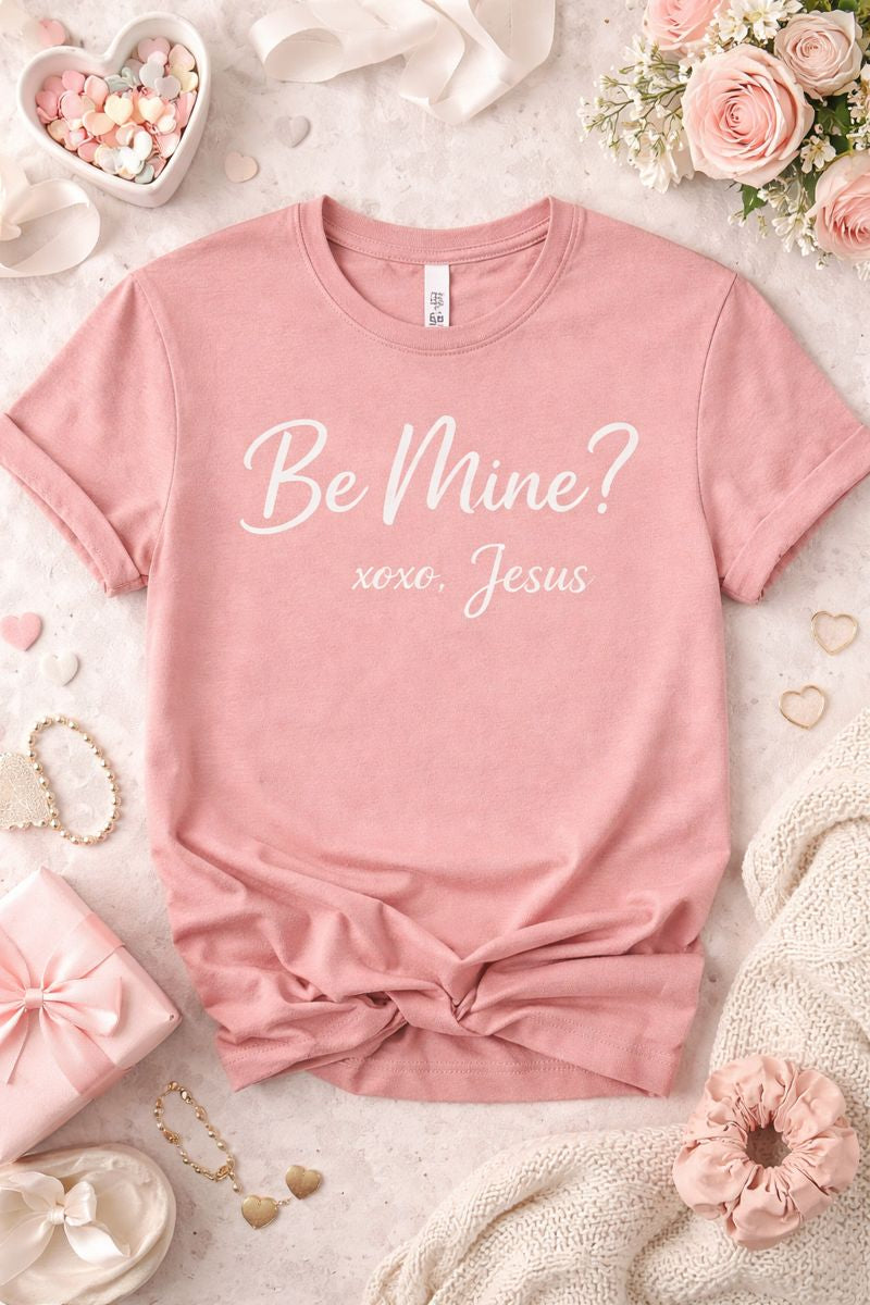 Blush Bella Canvas women’s t-shirt featuring the phrase “Be Mine? xoxo, Jesus” in soft cursive lettering with a faith-inspired Valentine aesthetic.